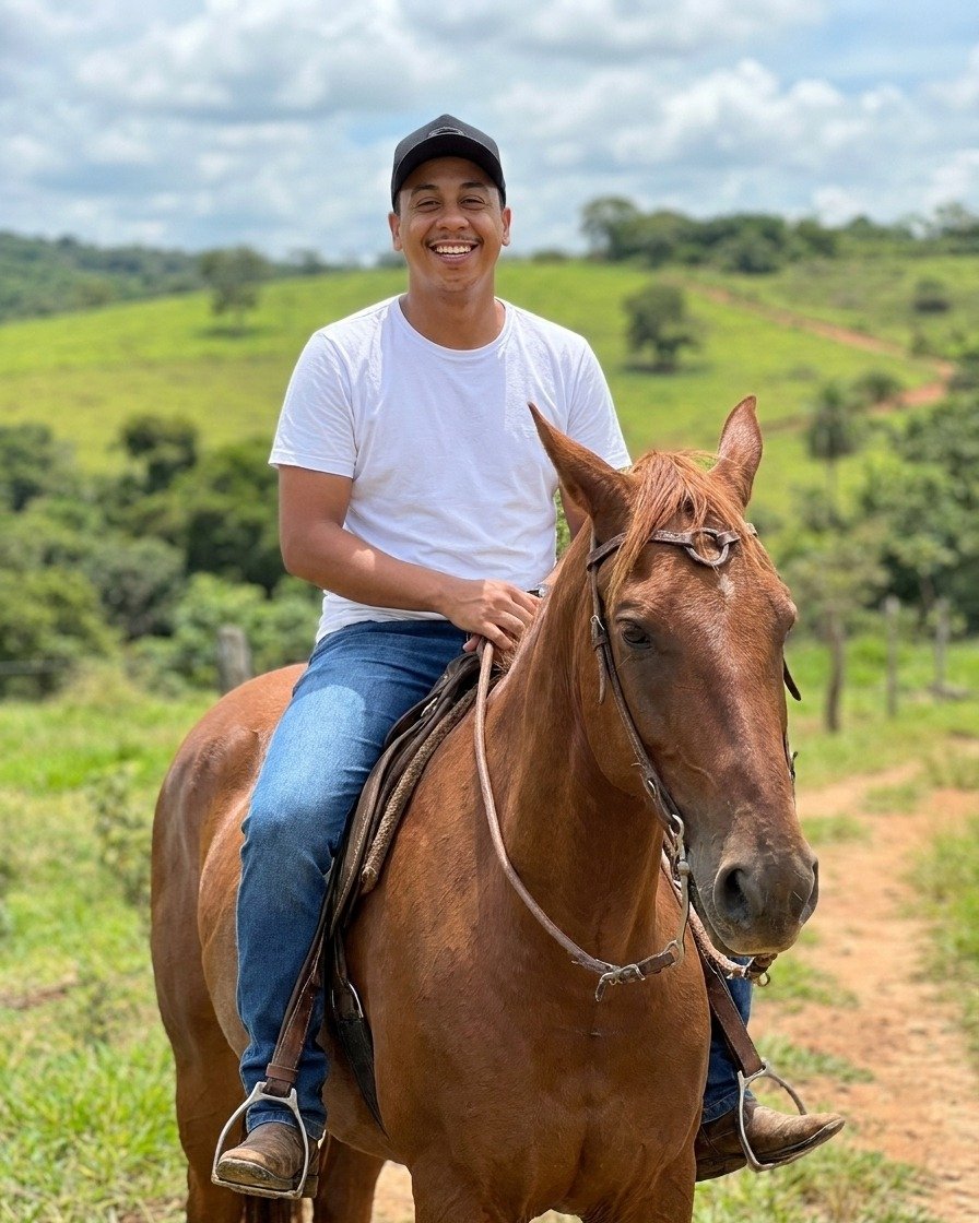 Jão sorrindo montado a cavalo na roça
